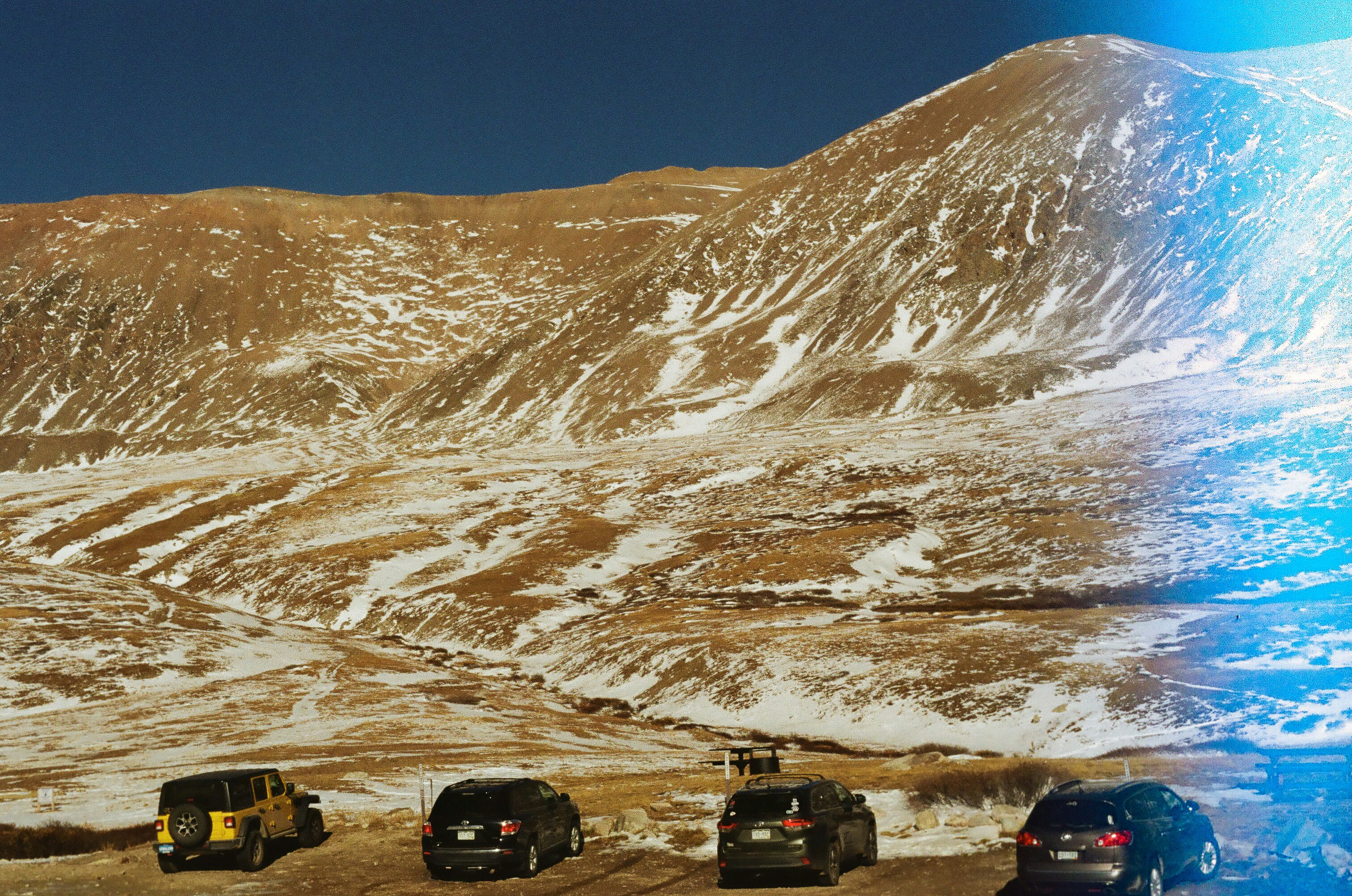 a group of cars parked in front of a snow covered mountain, burnt but cool
