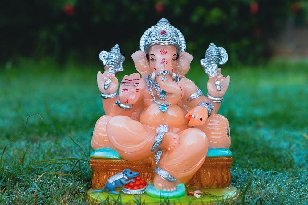 a statue of an elephant sitting on top of a lush green field