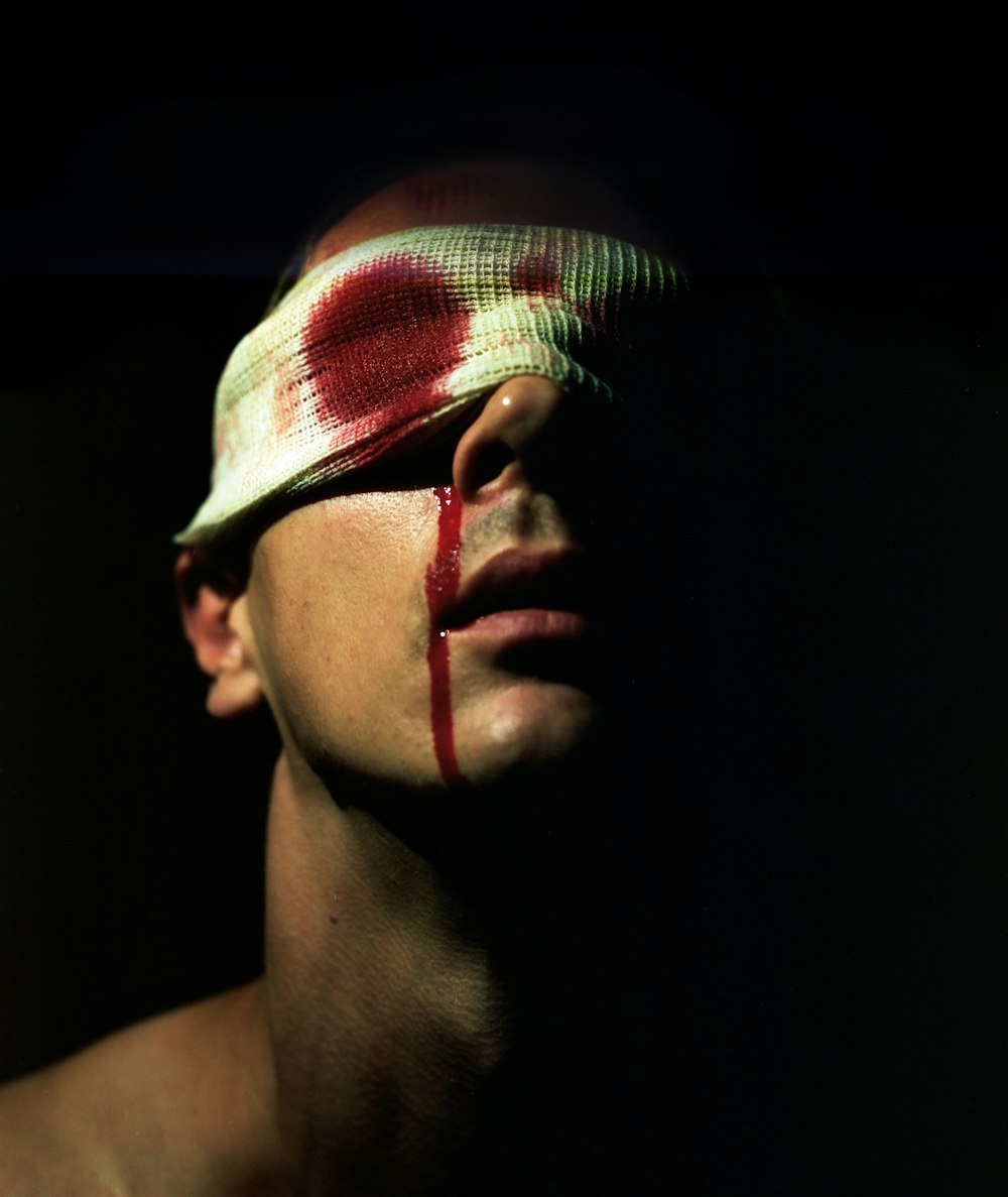 a man with a bandage on his head and a red cross painted on his face