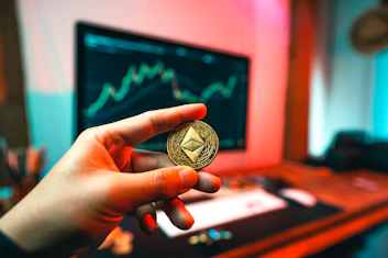 a person holding a coin in front of a computer