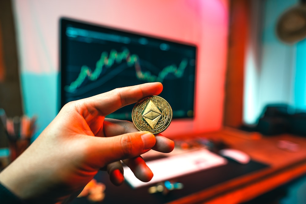 a person holding a coin in front of a computer