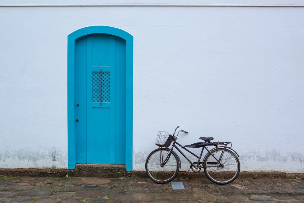 a bike parked next to a white building with a blue door