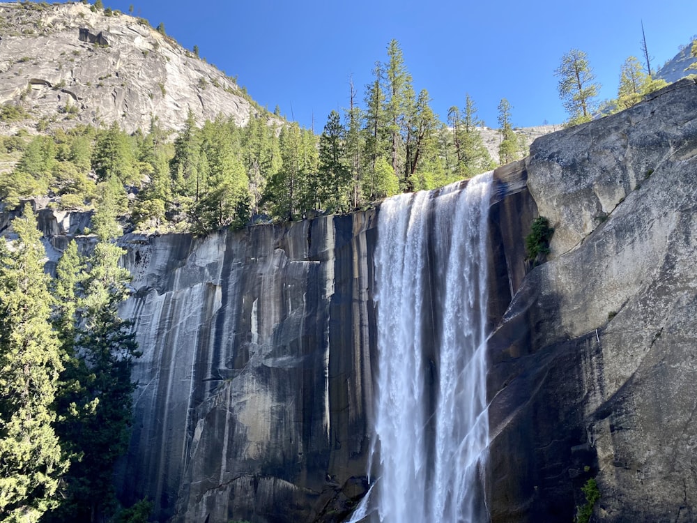 a large waterfall with a forest in the background