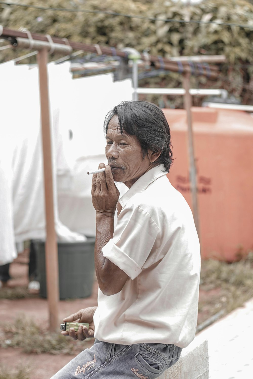 a man sitting on a bench smoking a cigarette