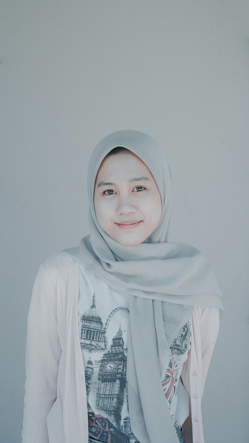 a woman wearing a headscarf standing in front of a white wall