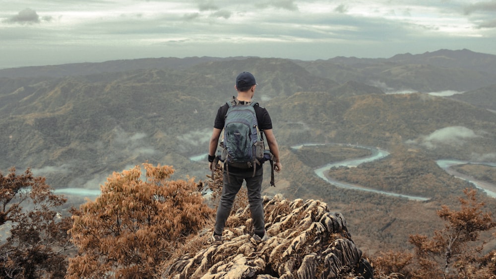 um homem em pé no topo de uma montanha com uma mochila