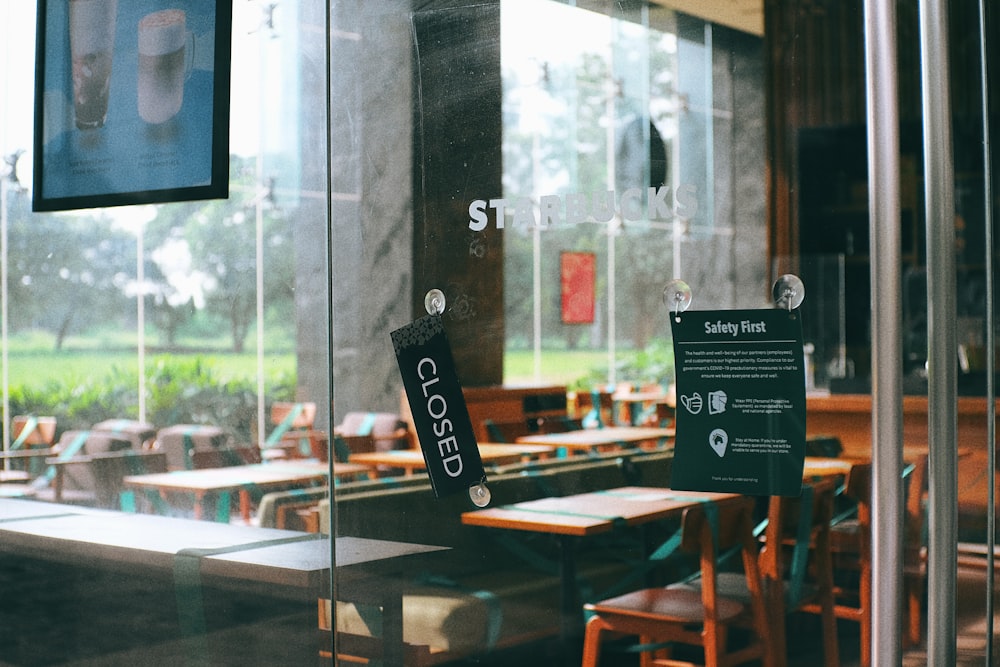 a restaurant with tables and chairs and a sign on the glass