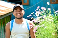 A smiling handyman wearing a 502fixes cap, standing proudly beside a perfectly manicured lawn.