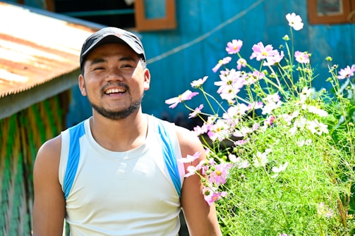 A smiling farmer standing proudly among rows of hydrangea plants.