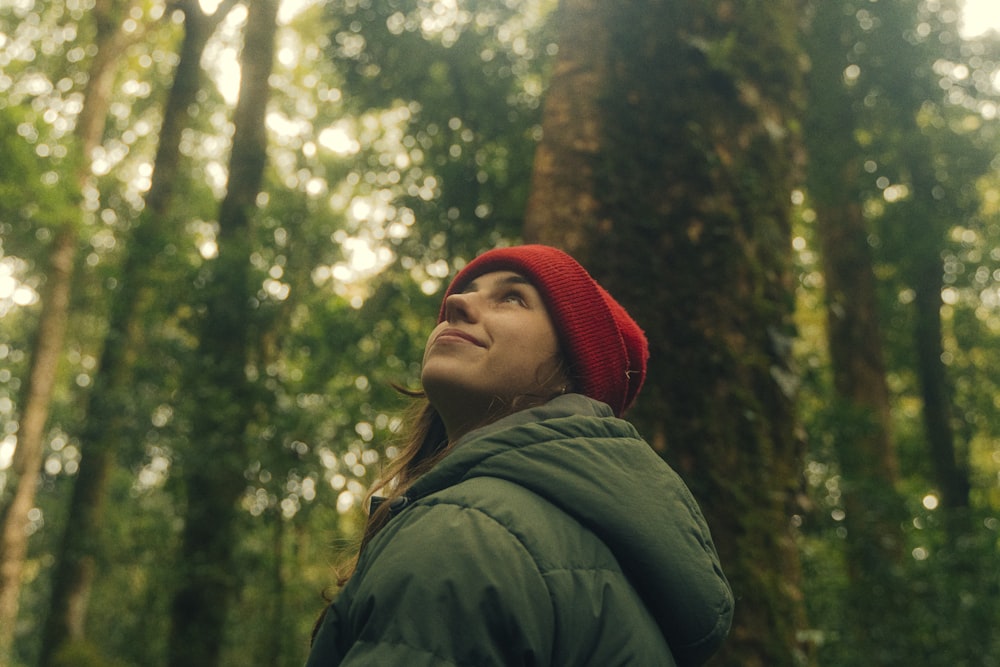 a woman in a red hat looking up at a tree