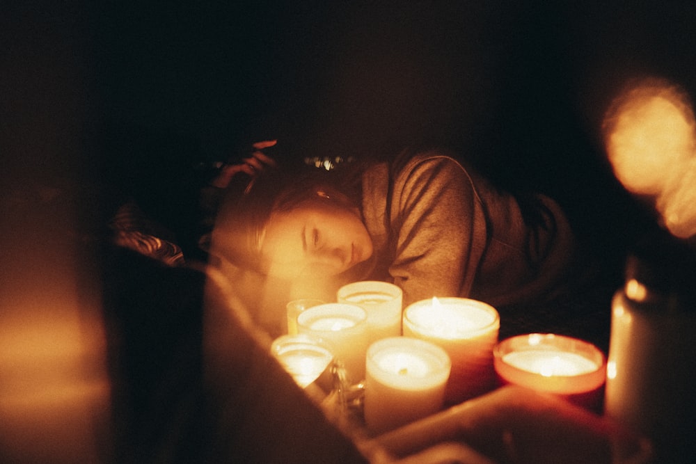 a woman laying down next to a bunch of candles