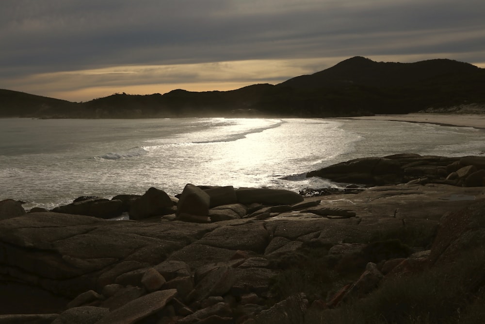 a body of water surrounded by rocks under a cloudy sky