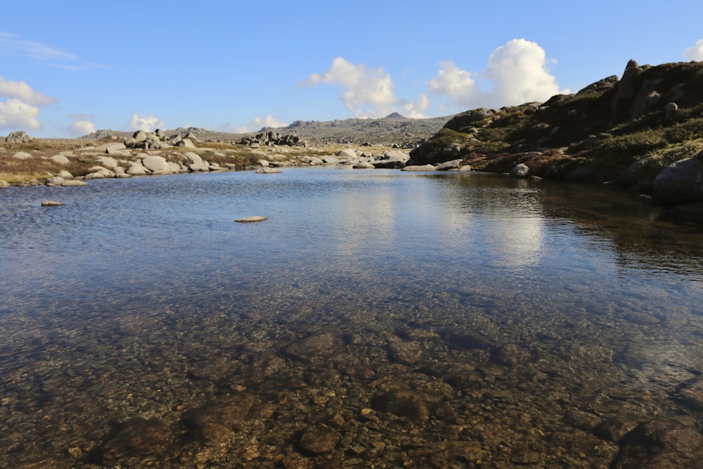 a body of water surrounded by rocks and grass