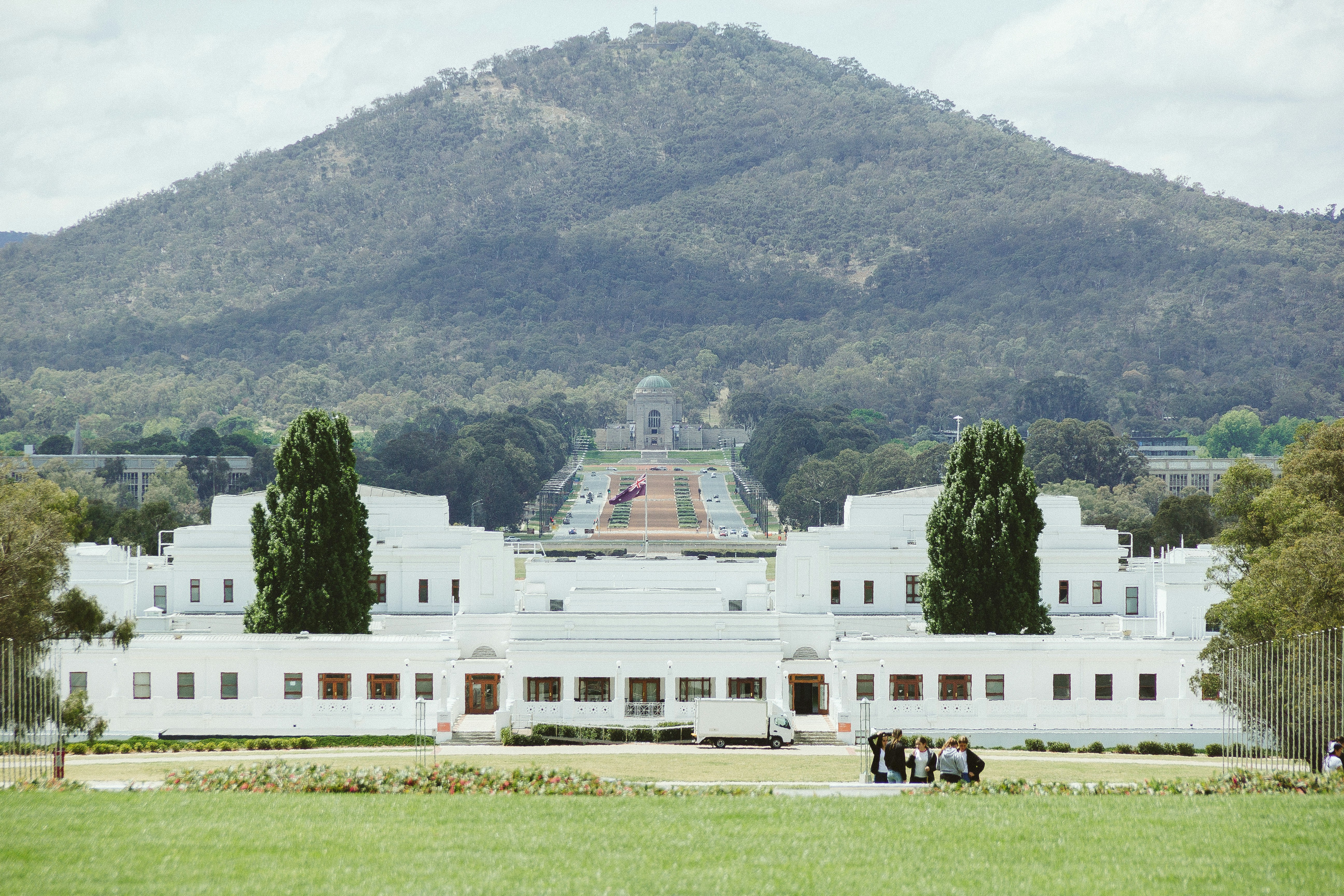 a large white building with a mountain in the background