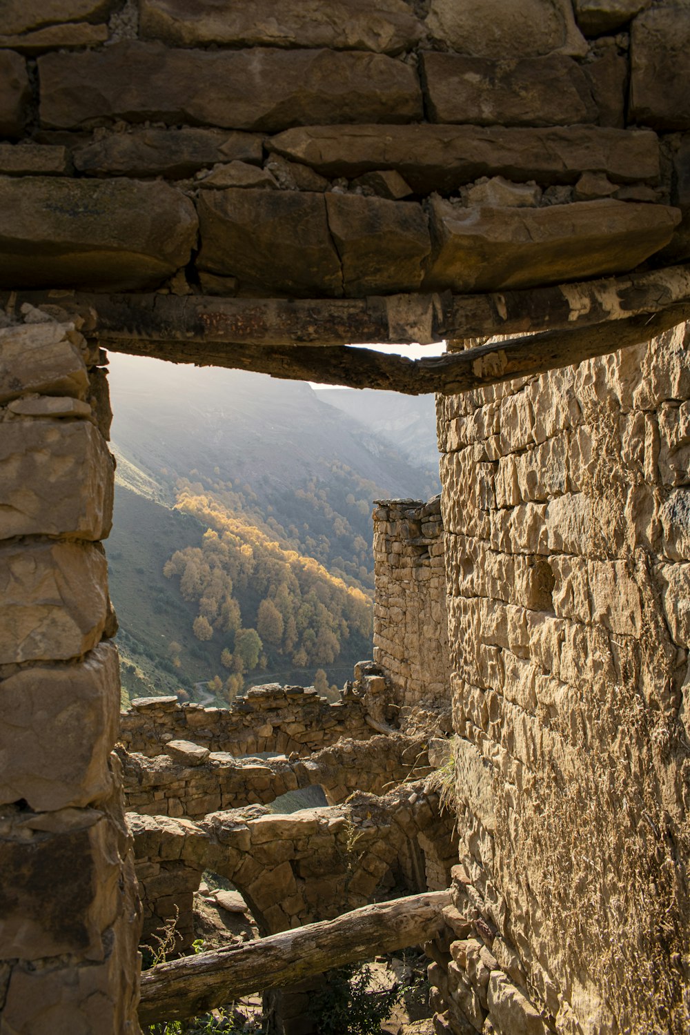 a window in a stone building with a view of mountains
