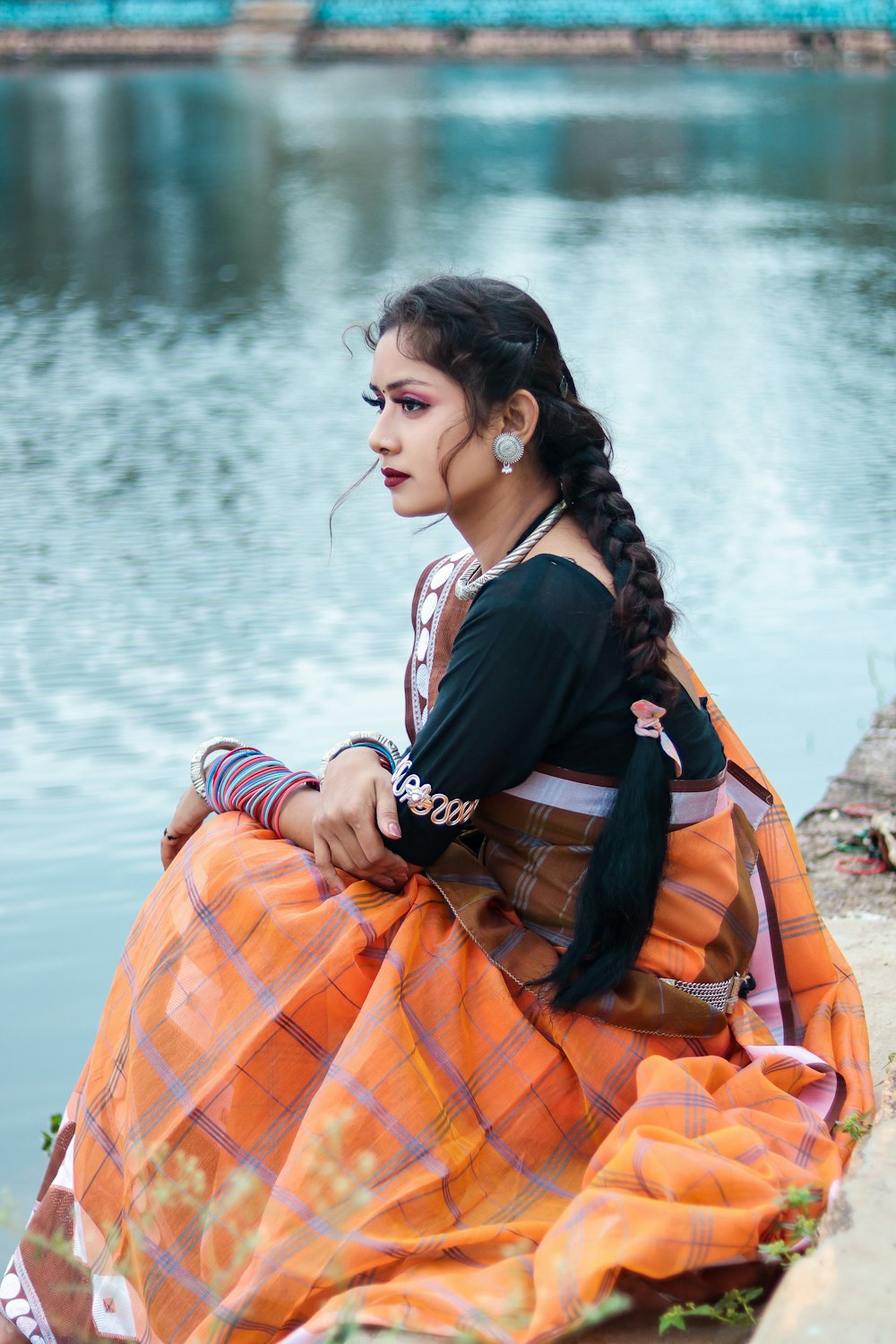 a woman sitting on the ground next to a body of water