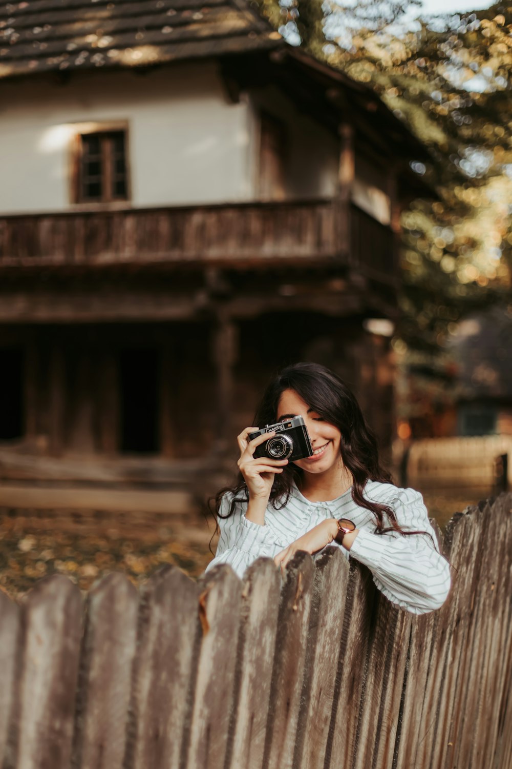 a woman taking a picture of a house through a fence