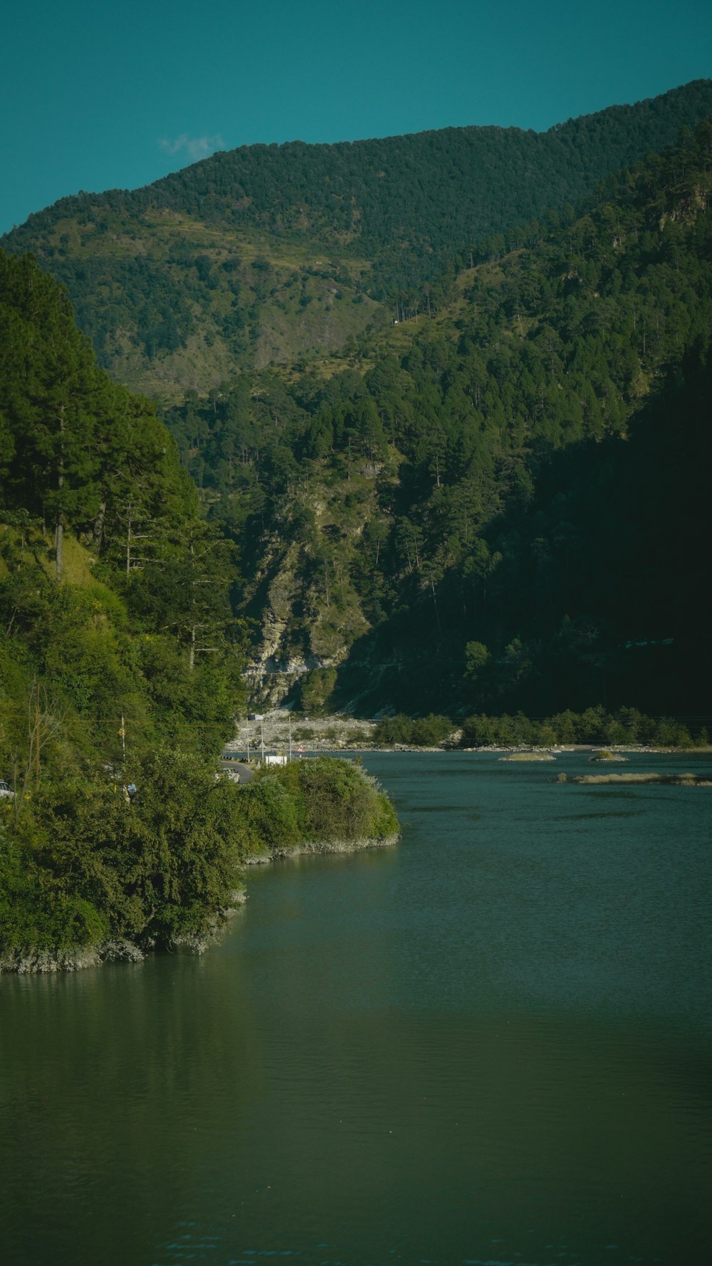 a body of water surrounded by a lush green hillside