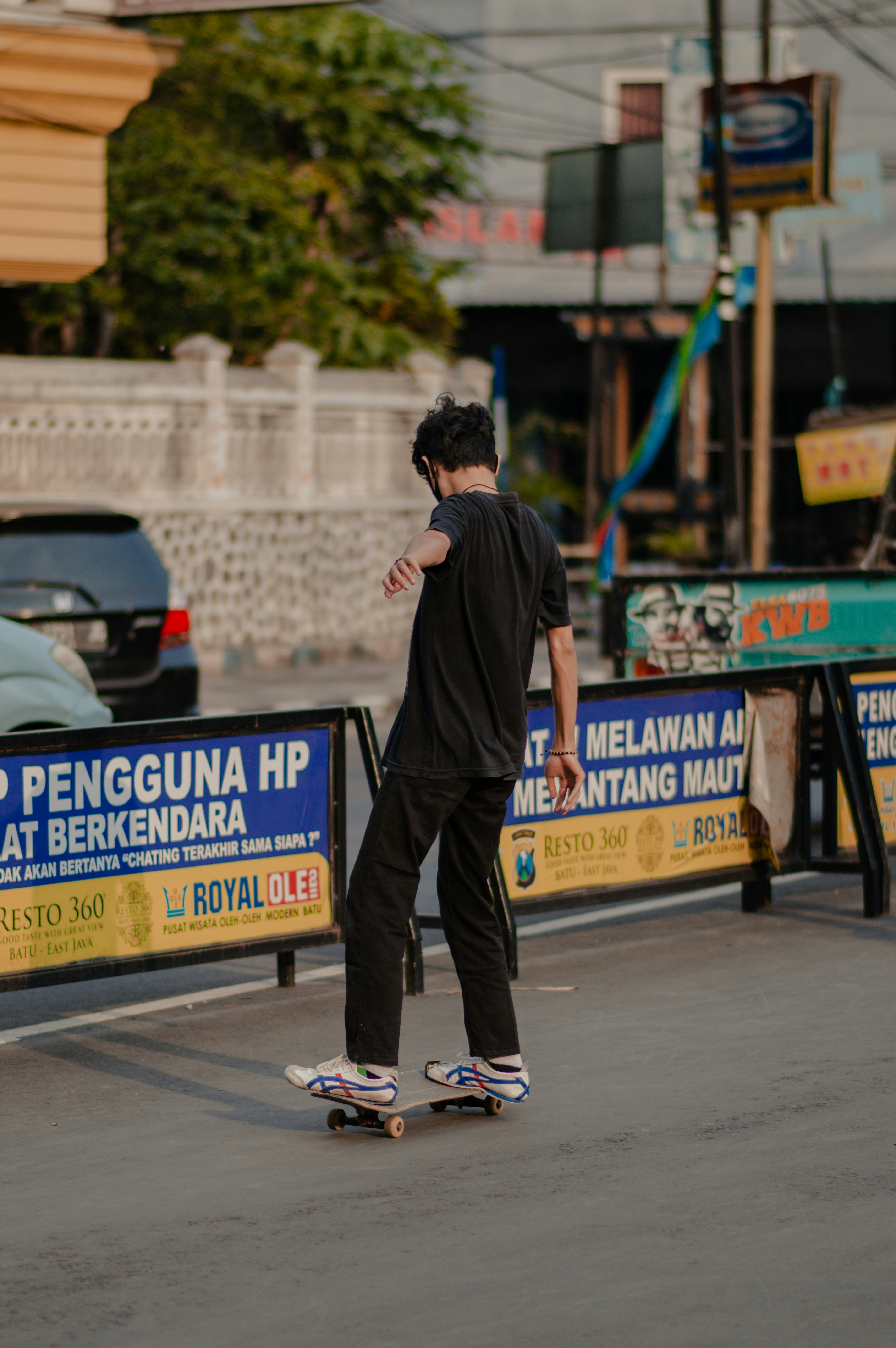seorang pemuda mengendarai skateboard di pinggir jalan
