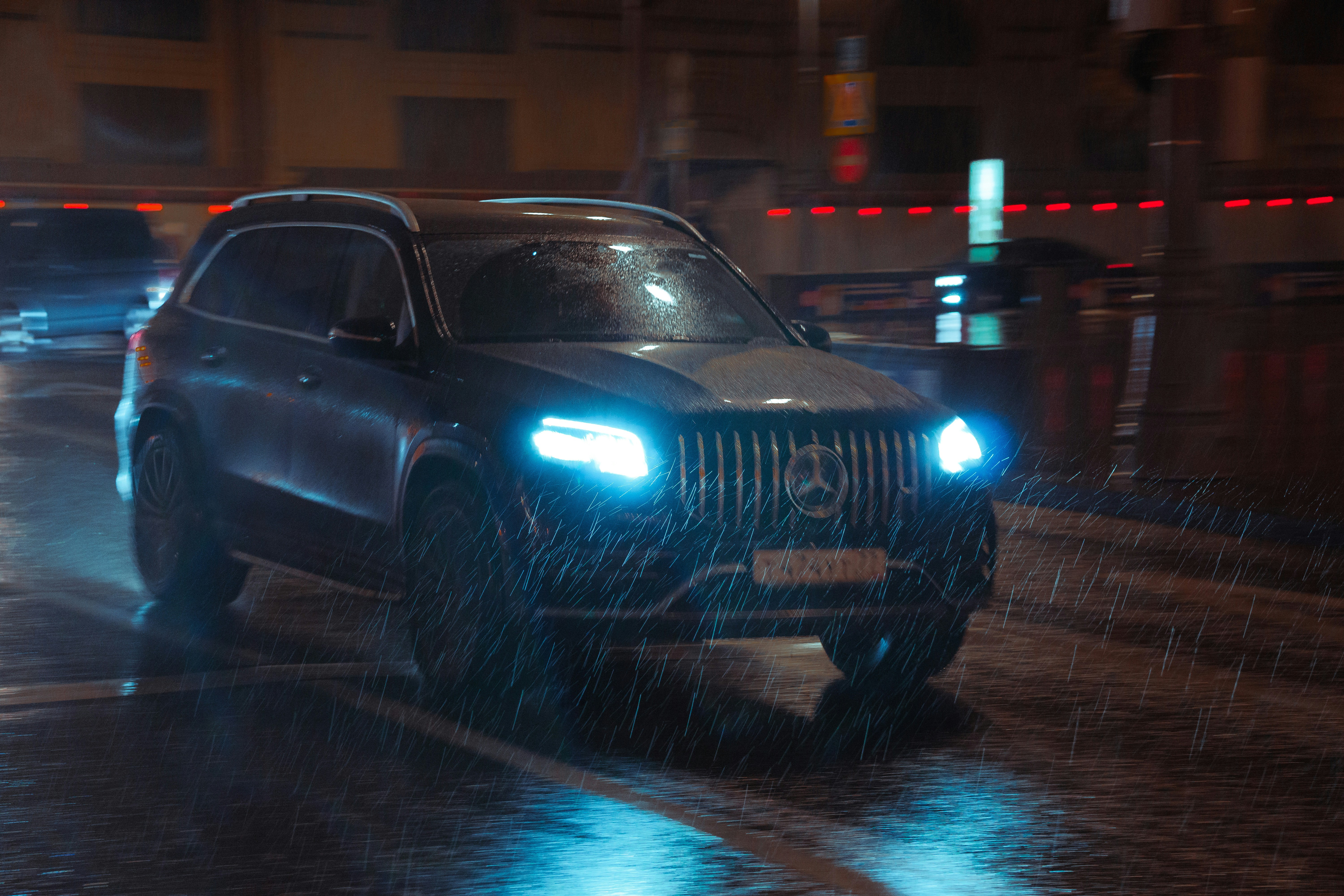 A black suv driving down a street in the rain photo – Free Car Image on ...