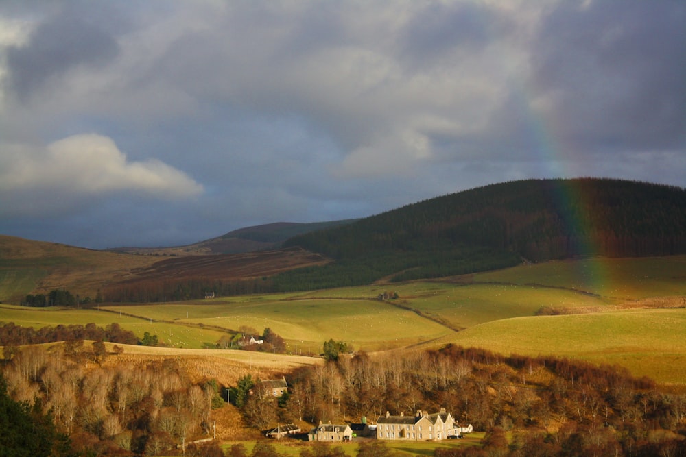 a rainbow shines in the sky over a farm