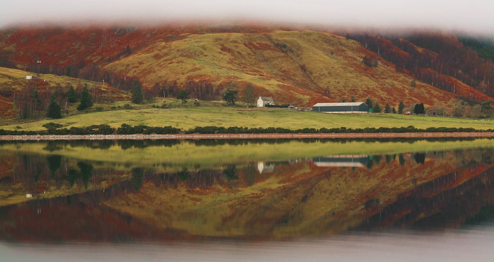 a house on the side of a mountain next to a body of water