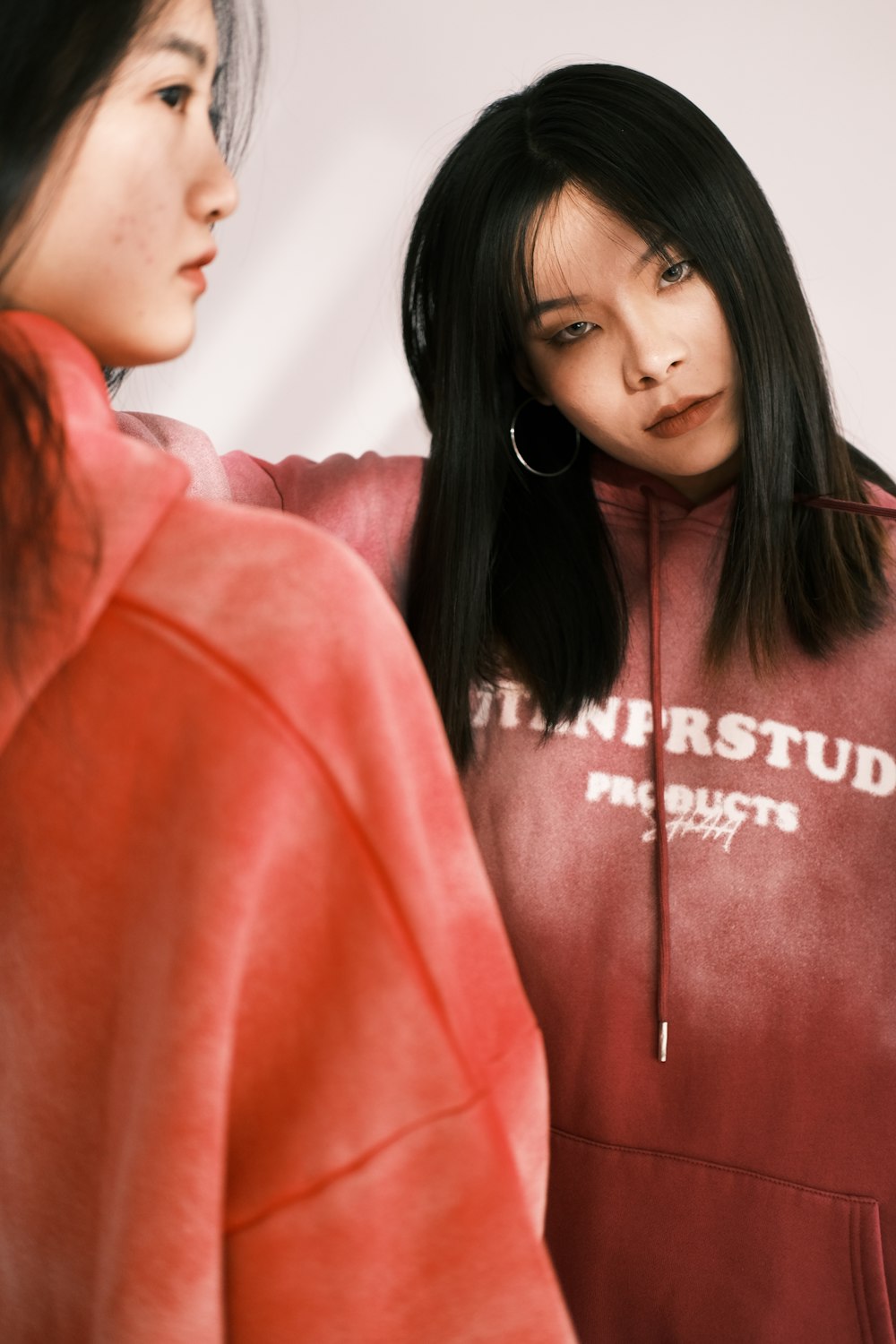 a woman in a red hoodie looking at another woman in a red hoodie