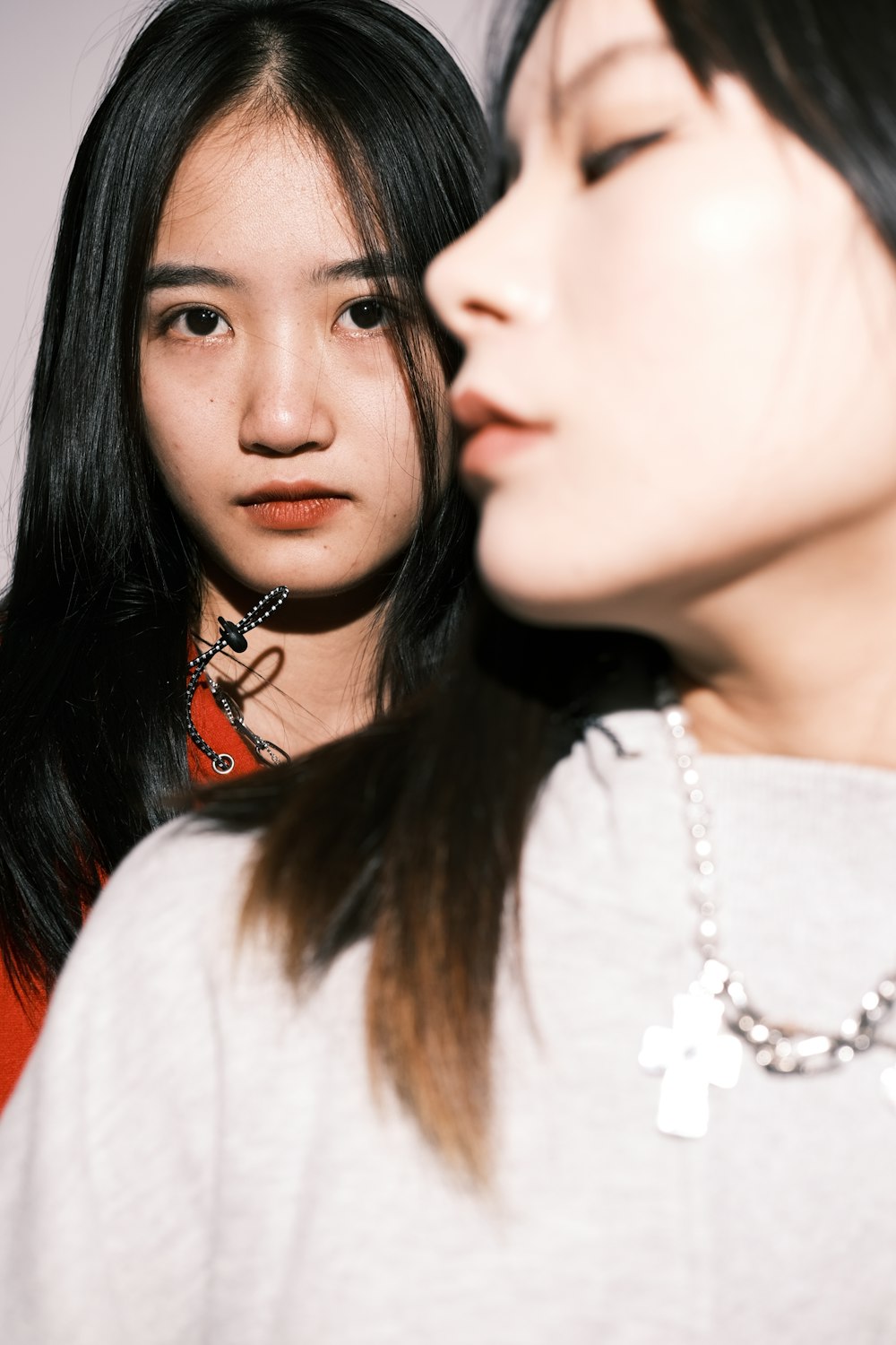 two women standing next to each other with a necklace on