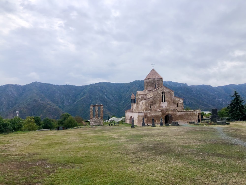 Una antigua iglesia en un campo con montañas al fondo