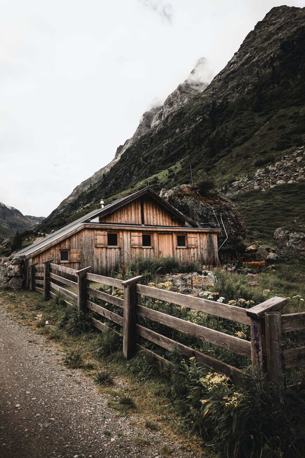 a wooden house sitting on top of a lush green hillside