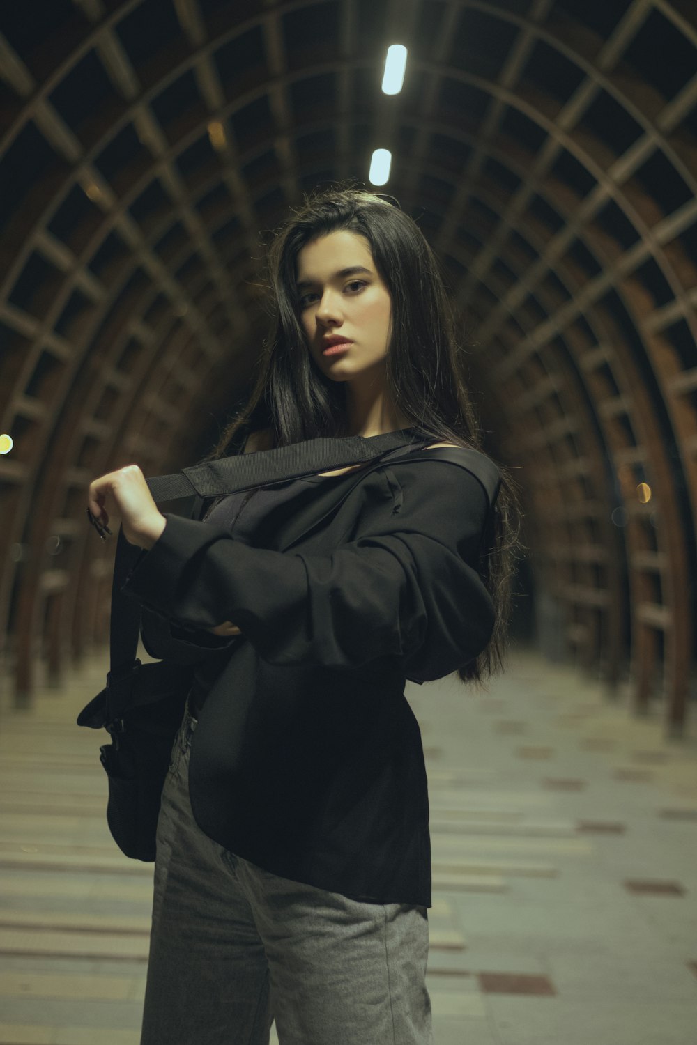 a woman standing in a tunnel with her arms crossed