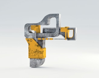 A modern, industrial-shaped structure made of metallic gray and yellow elements, featuring geometric forms and detailed textures.
