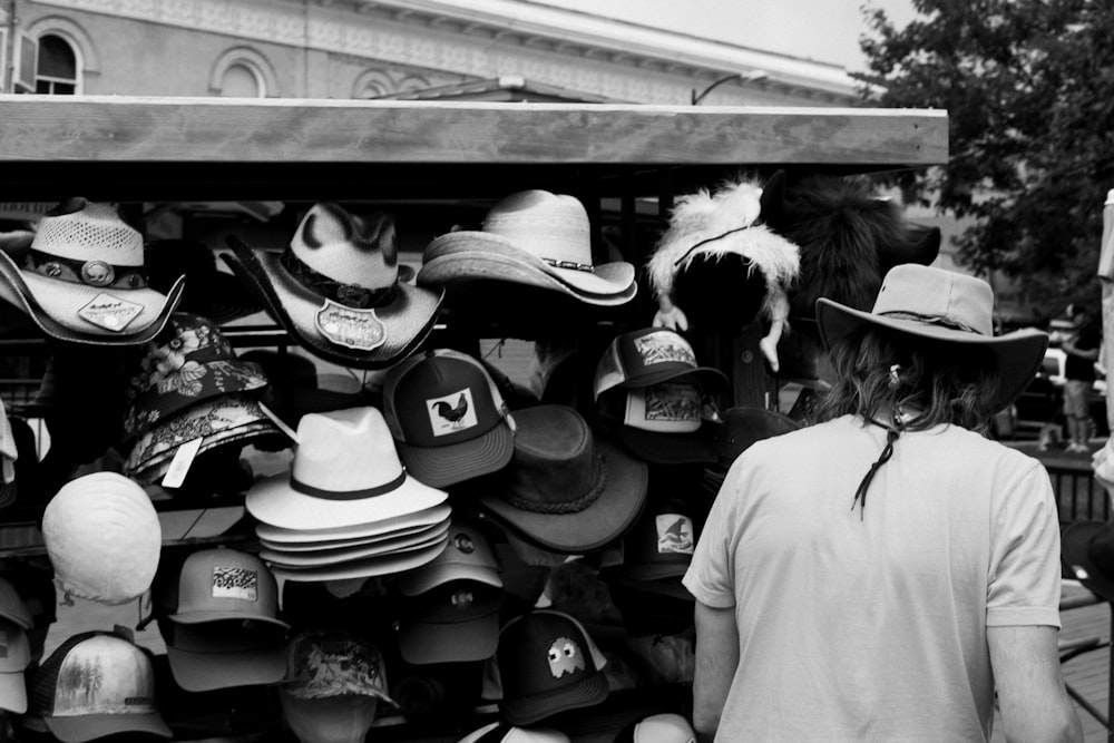 a woman is looking at hats on display