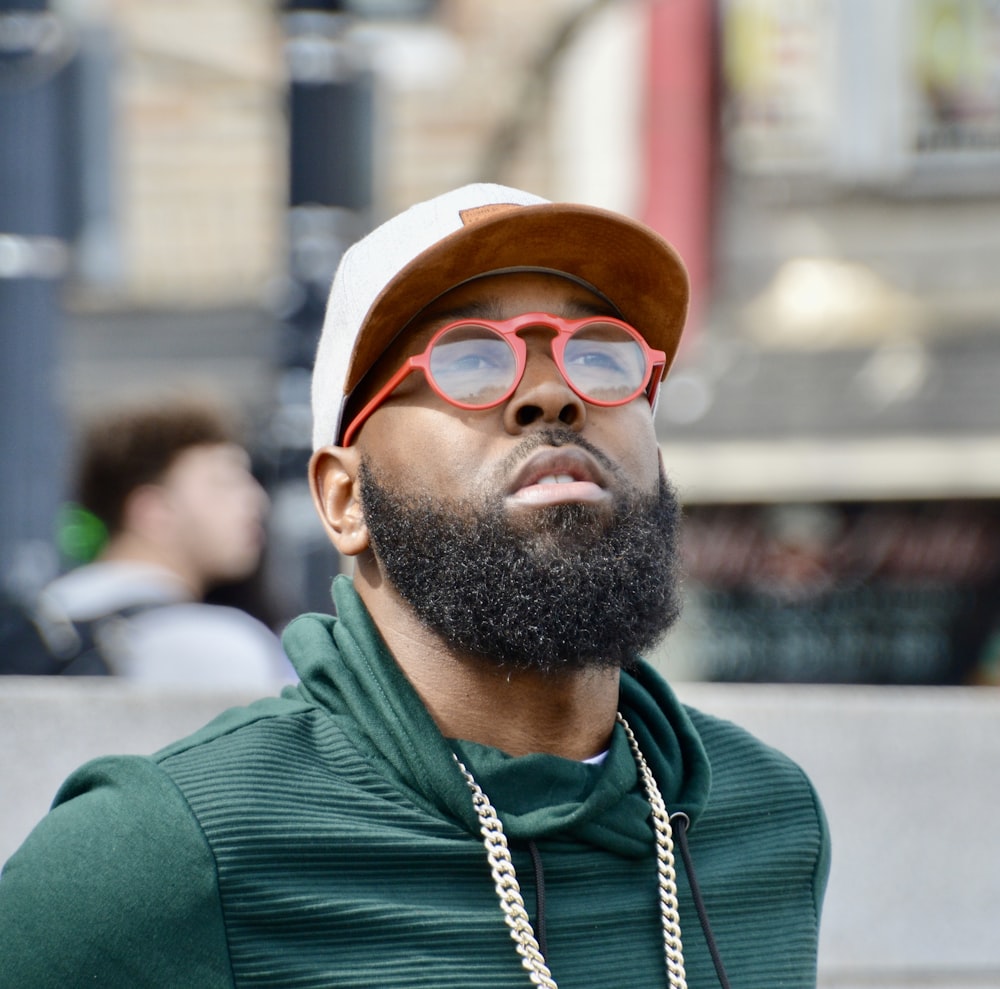 Un uomo con la barba che indossa occhiali da sole e un cappello