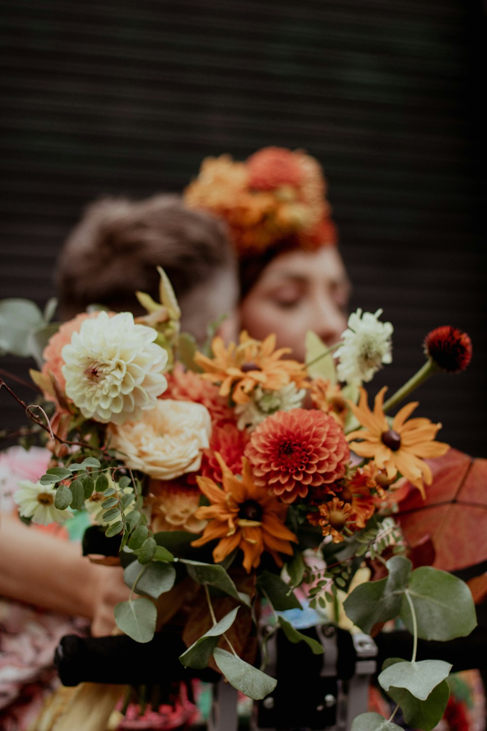 a couple of women standing next to each other holding a bouquet of flowers