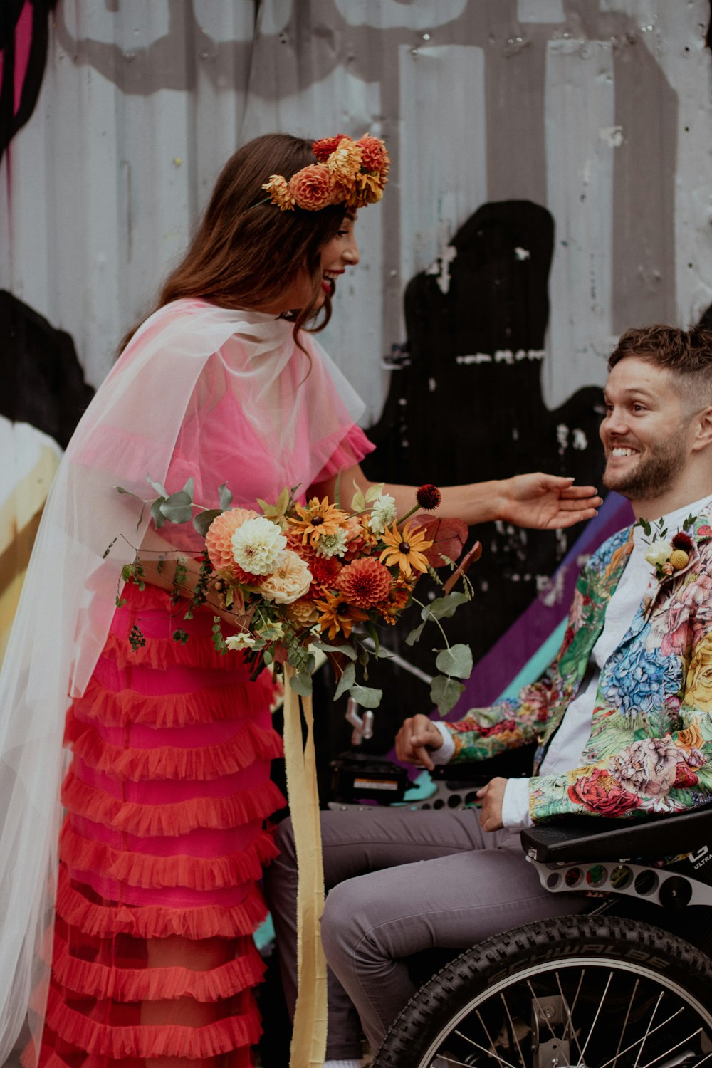 um homem em uma cadeira de rodas segurando um buquê de flores ao lado de uma mulher em um