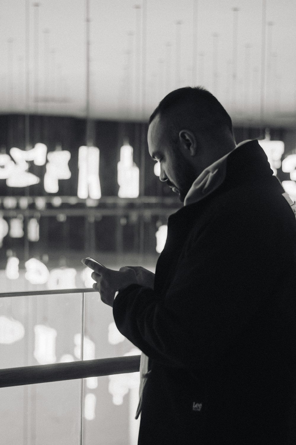 a man standing next to a window looking at his cell phone