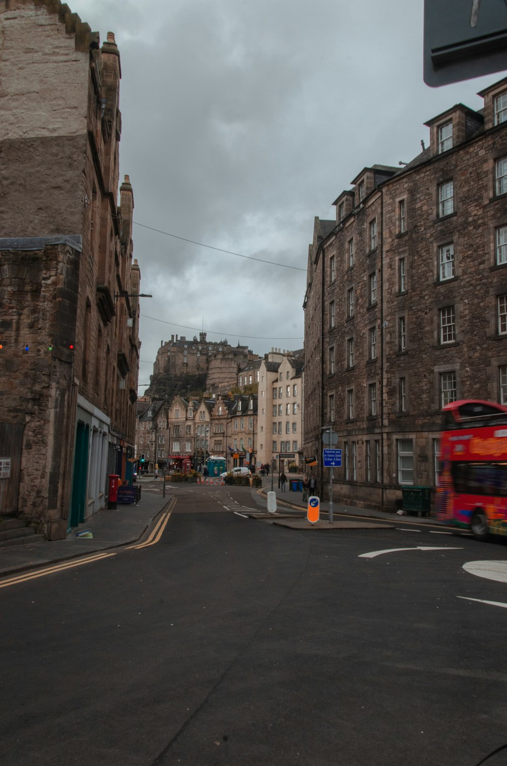 a red bus driving down a street next to tall buildings