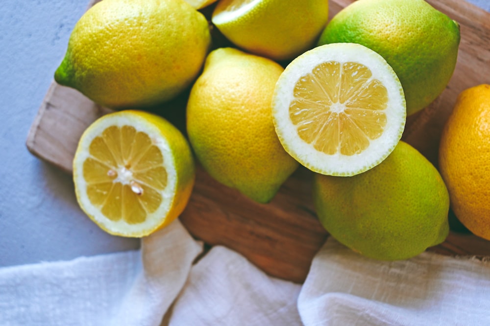 a wooden cutting board topped with lemons and limes