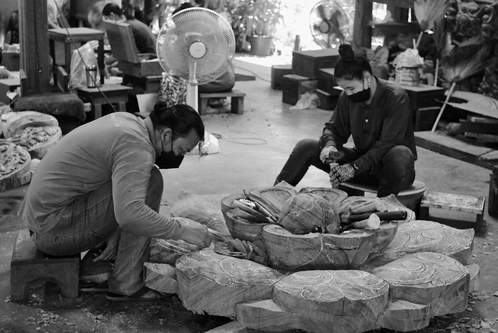 a black and white photo of a man working on a piece of wood