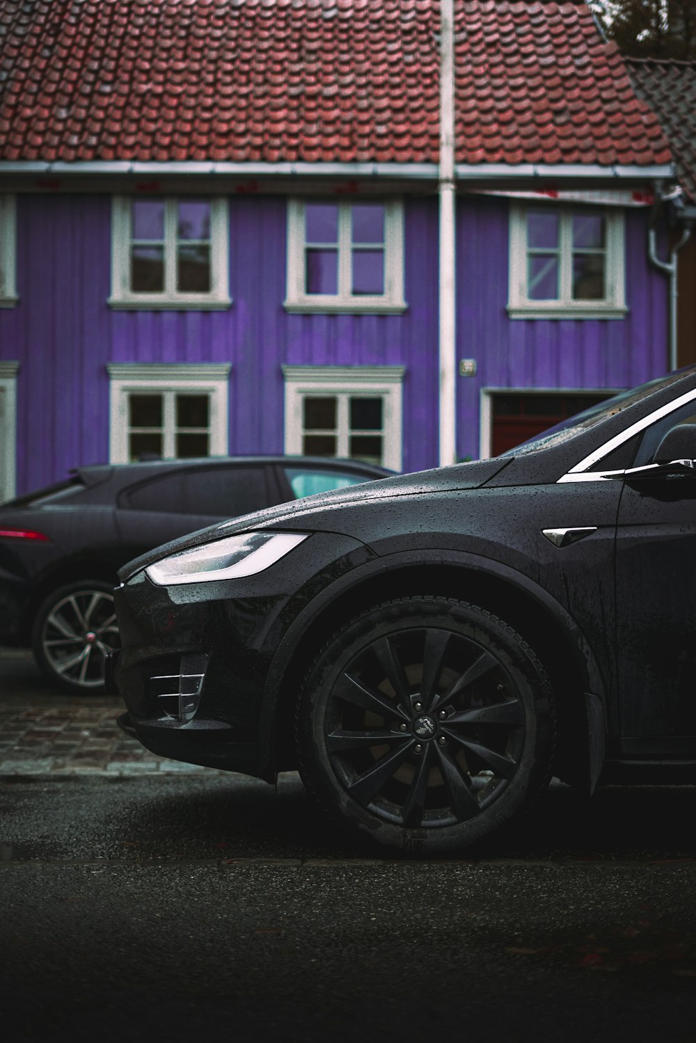 a black car parked in front of a purple house