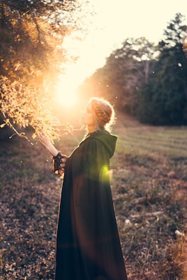 a woman in a long dress holding a stick in a field