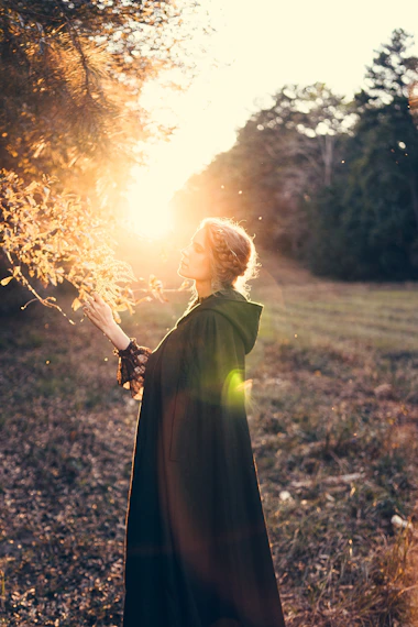 a woman in a long dress holding a stick in a field