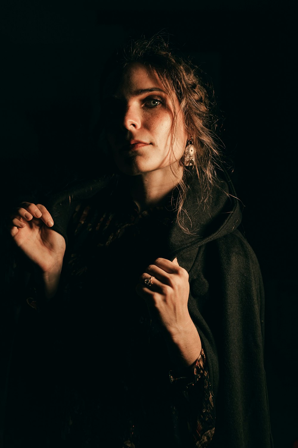 a woman standing in the dark with her hands on her chest