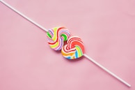 two lollipops sitting on top of a pink surface