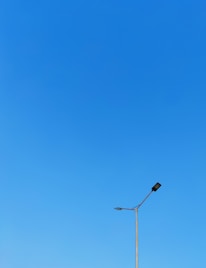 Minimalist black-and-white image of a sleek solar street light against a clear sky.