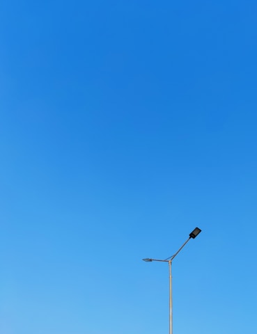 Minimalist black-and-white image of a sleek solar street light against a clear sky.