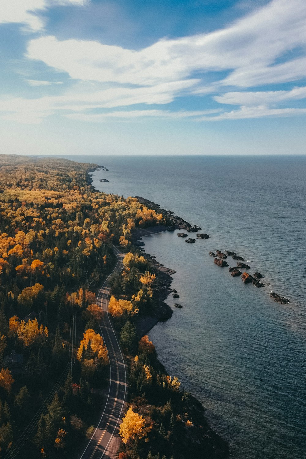 an aerial view of a road next to a body of water