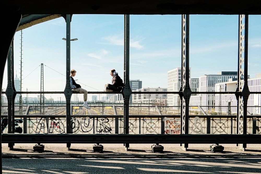 a couple of people sitting on top of a bridge