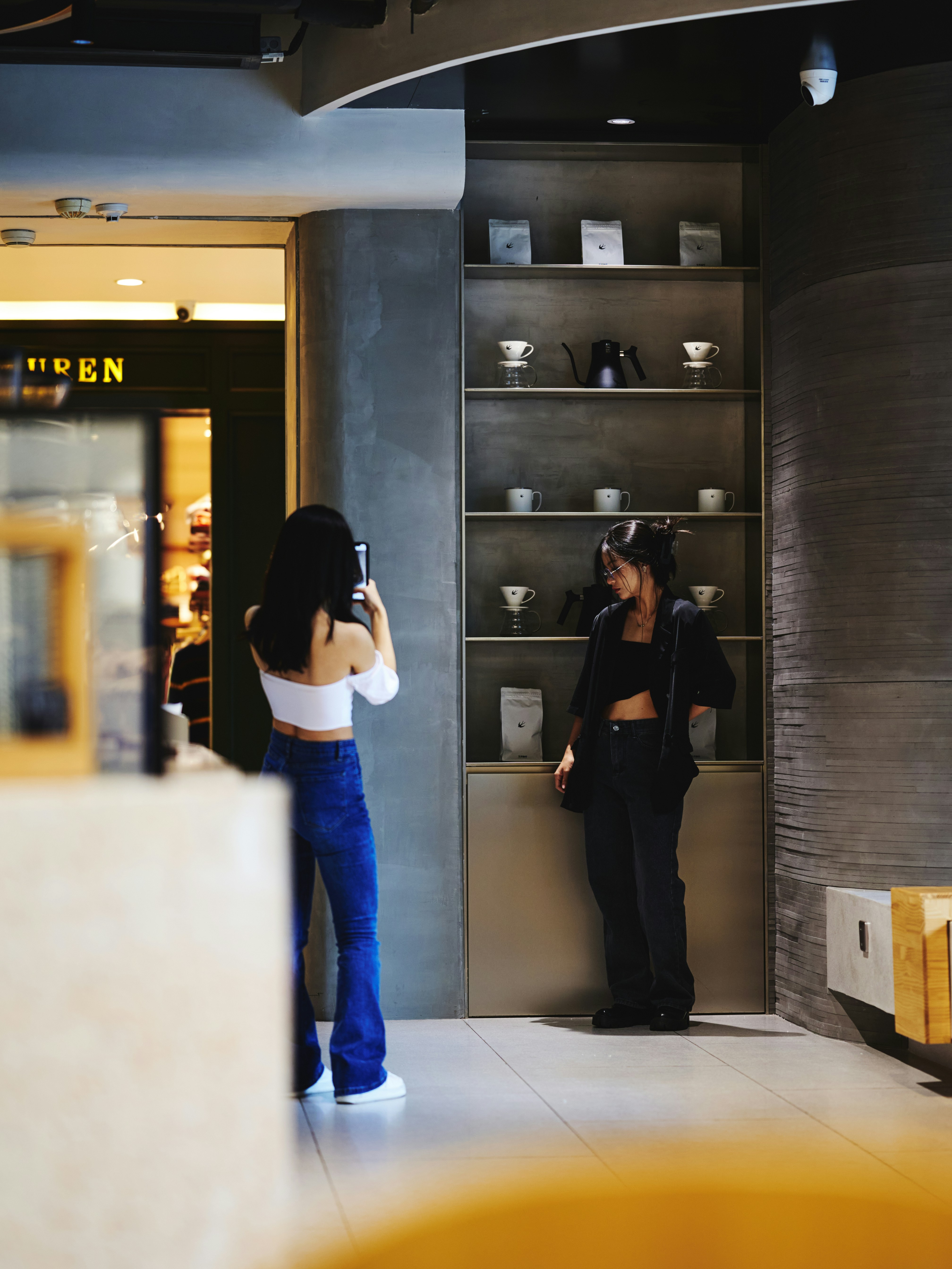 Deux femmes photographient du matériel de café avec un smartphone.